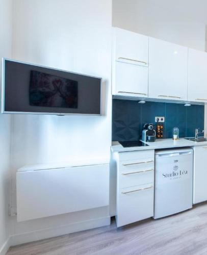 Il comprend une cuisine avec des placards blancs et une télévision murale. dans l'établissement Studio Léa, à Cannes