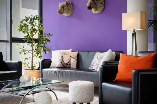 a living room with a purple wall and a couch at Best Western Macrander Hotel Dresden in Dresden