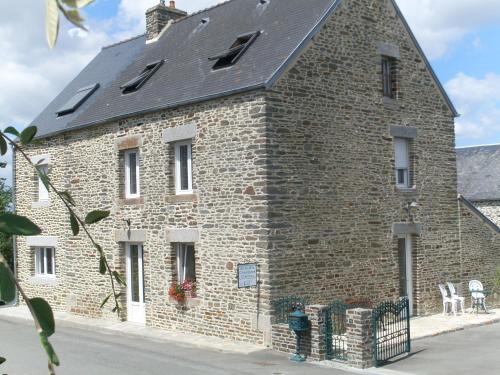 un ancien bâtiment en briques avec un toit noir dans l'établissement Chambres D'hôtes au Saint Avit, à Huisnes-sur-Mer