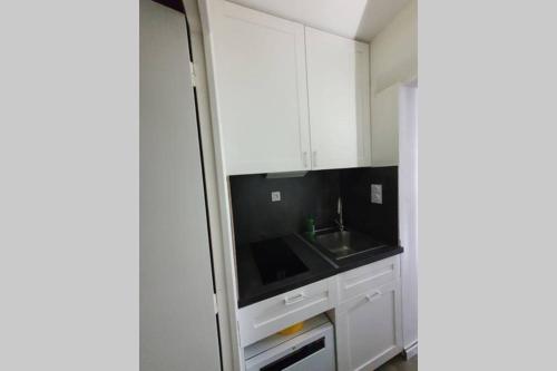 a kitchen with white cabinets and a black counter top at Appartement Loire et Château, Hyper Centre, vue Loire, Linge inclus, 3ème étage in Saumur