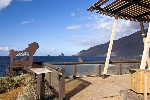 una terraza de madera con un banco y el océano en EL AGAVE DE MERESE APARTAMENTO, en Las Toscas