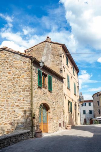 an old stone building with a yellow door and green shutters at Holiday Home La Suite del Benessere by Interhome in Seggiano
