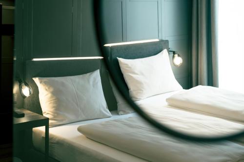 フェルデン・アム・ヴェルターゼーにあるRocket Rooms Veldenの白い枕と鏡付きのベッド2台が備わる客室です。