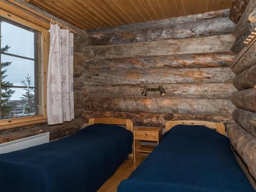 two beds in a room with wooden walls at Holiday Home Ahmanportti 2 by Interhome in Ylläs