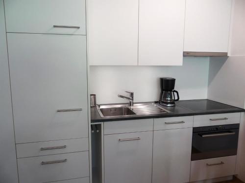 una cocina con armarios blancos y fregadero en Apartment Erlenrain Wohnung 722E by Interhome, en Engelberg