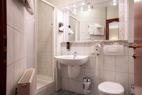 a white bathroom with a sink and a toilet at Aparthotel Hohenzollern in Bad Kissingen