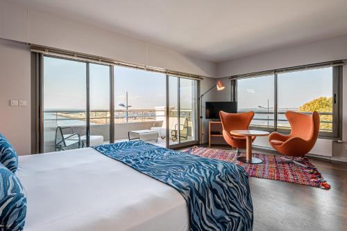 une chambre d'hôtel avec un lit, des chaises et des fenêtres dans l'établissement Anne de Bretagne, à La Plaine-sur-Mer