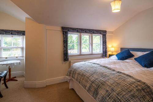 a bedroom with a bed and two windows at Otter View in Kendal