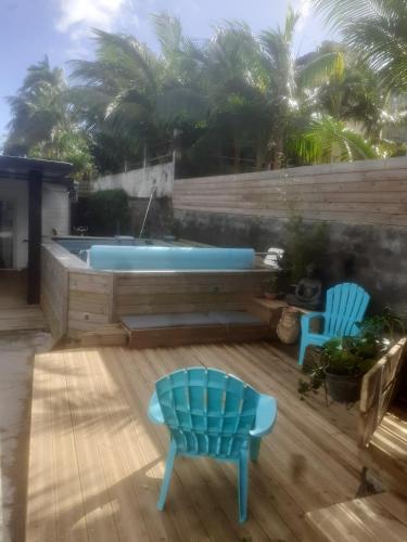 a hot tub on a deck with two chairs and a chair at Charmante Maison à Saint Philippe avec Piscine Privée in Saint-Philippe