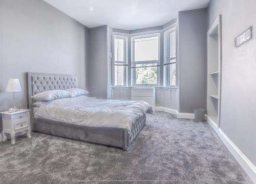 a white bedroom with a bed and a window at Beautiful modern open plan living with Hot Tub in Kelty