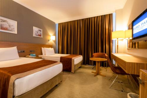 a hotel room with two beds and a flat screen tv at Euro Park Hotel Bursa in Bursa