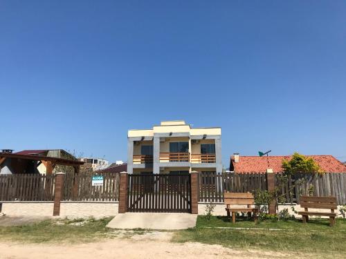 a house with a fence and two benches in front of it at Residencial Berê in Palhoça