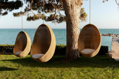 two wooden swings hanging from a tree near the water at ME Ibiza - The Leading Hotels of the World in Santa Eularia des Riu
