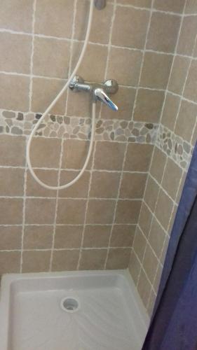 une douche avec un tuyau sur un mur carrelé dans l'établissement Le petit coin tranquille, à Signes