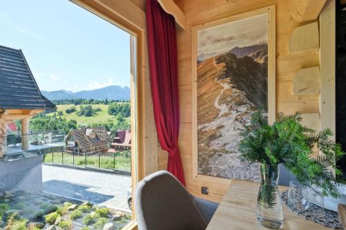 a dining room with a table and a large window at Osada Bachledzki Wierch Odkryj Zakopane in Zakopane
