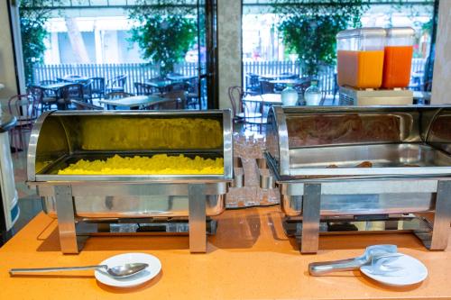 two containers of food sitting on a table with spoons at Hotel Olanda in Lido di Jesolo