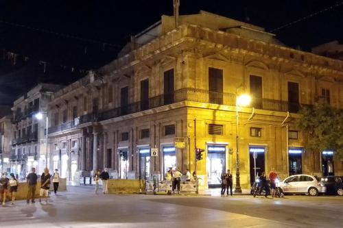 un edificio amarillo en una calle de la ciudad por la noche en Palazzo Galati Palermo, en Palermo