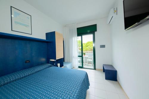 1 dormitorio con cama azul y balcón en Hotel Olanda, en Lido di Jesolo