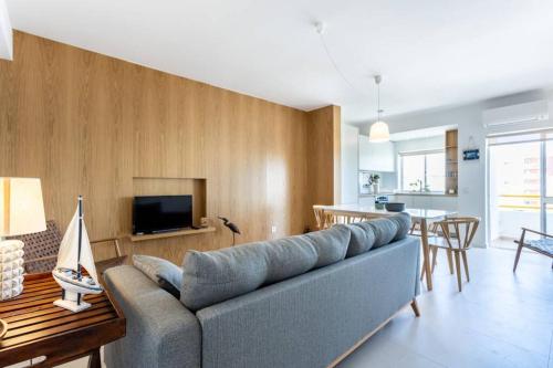 a living room with a blue couch and a kitchen at Cozy ap renovado 1ª linha de Praia - Armação Pêra in Armação de Pêra