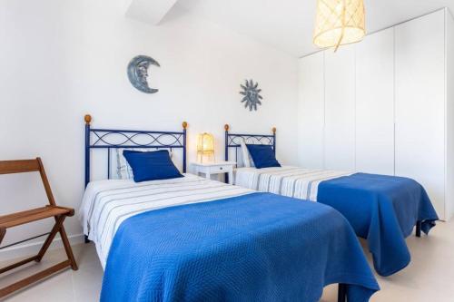 two beds in a room with blue and white sheets at Cozy ap renovado 1ª linha de Praia - Armação Pêra in Armação de Pêra