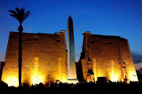 a tall building with a palm tree and a obelisk at El Mesala Hotel in Luxor