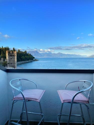 two chairs on a balcony with a view of the water at Hotel Grifone in Sirmione