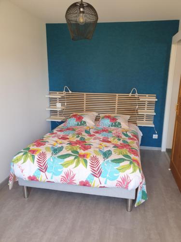 1 dormitorio con 1 cama con un edredón colorido en T2 CHEZ LE MARECHAL à NEBOUZAT, en Nébouzat