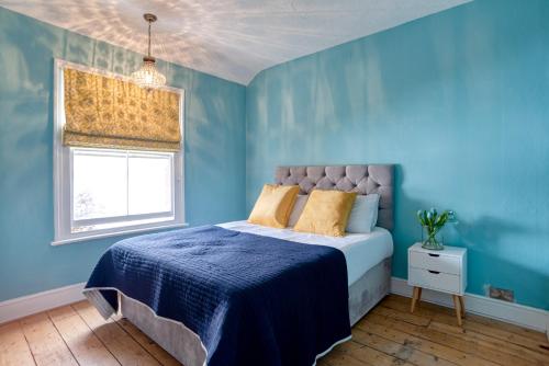 a blue bedroom with a bed and a window at The Beach House - Cromer in Cromer