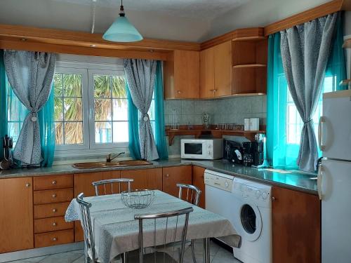 a kitchen with a table and a kitchen with blue curtains at Villa Stegna in Archangelos