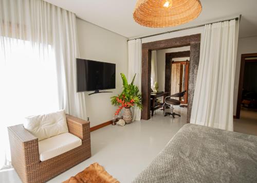 a bedroom with a bed and a chair and a television at Kaza Mazamore - Entire luxurious Vila in Itaunas. in Conceição da Barra