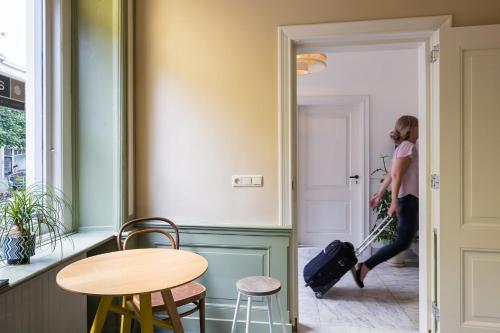 a woman walking through a room with a suitcase at Stadshotel Steegoversloot in Dordrecht