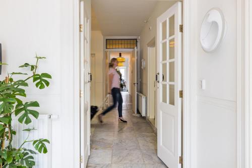 a woman walking down a hallway in a house at Stadshotel Steegoversloot in Dordrecht