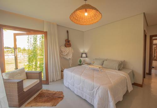 a bedroom with a bed and a guitar on the wall at Kaza Mazamore - Entire luxurious Vila in Itaunas. in Conceição da Barra