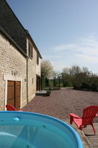 un patio avec deux chaises rouges et un bâtiment dans l'établissement Domaine Des Hêtres, à Longraye