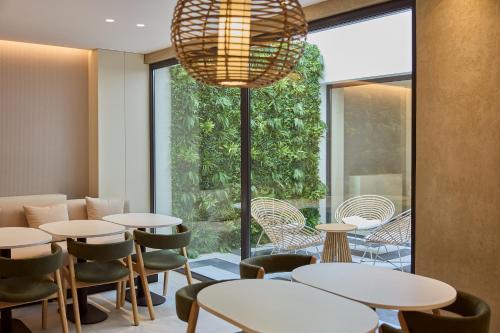 a restaurant with tables and chairs and a large window at OMID Saldanha Hotel in Lisbon