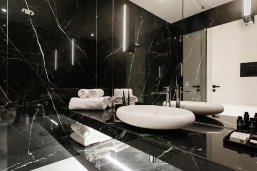 a bathroom with a sink and a black marble wall at Supreme Downtown Luxury Suites in Athens Riviera by The Olon in Athens