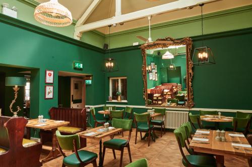 ウッドストックにあるThe Kings Armsの緑の壁と木製のテーブルと椅子が備わるレストラン