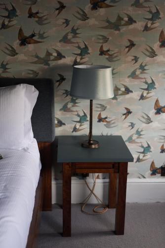a bedroom with a bed and a table with a lamp at The Kings Arms in Woodstock