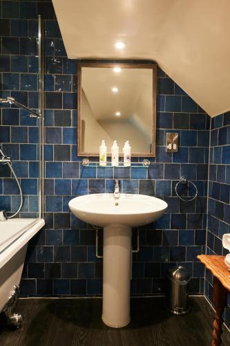 a blue tiled bathroom with a sink and a mirror at The Kings Arms in Woodstock