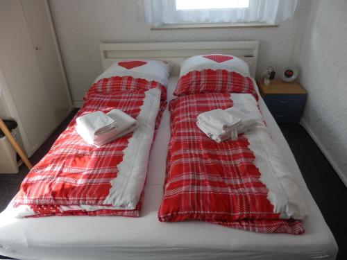two beds with red and white blankets on them at Gästezimmer Boxenstopp in Veitsbronn