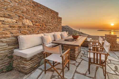 a patio with a couch and a table and chairs at IRIDA Villa - Sea & Sunset Flats by Explore Andros in Batsi