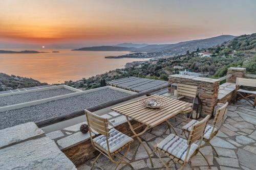 un patio con mesa y sillas y vistas al agua en IRIDA Villa - Sea & Sunset Flats near Batsi en Batsi