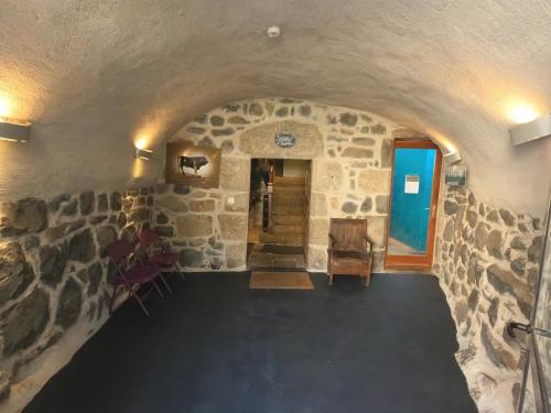 a room with a stone wall and a hallway at La Maison - Hôtel & Gîte in Laguiole