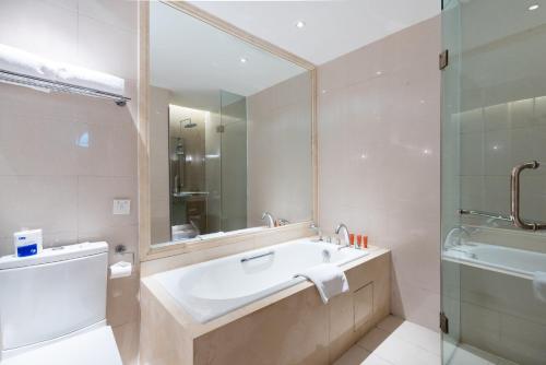a bathroom with a tub and a sink and a mirror at Tianjin Crown International Apartment in Tianjin