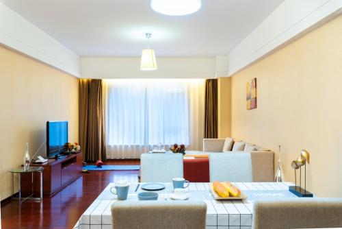 a living room with a couch and a table with chairs at Tianjin Crown International Apartment in Tianjin