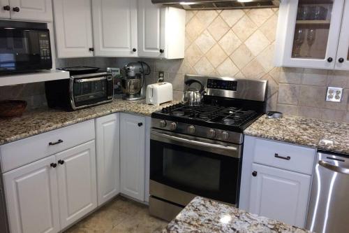 a kitchen with white cabinets and a stove top oven at Large family house on the lake in Hewitt