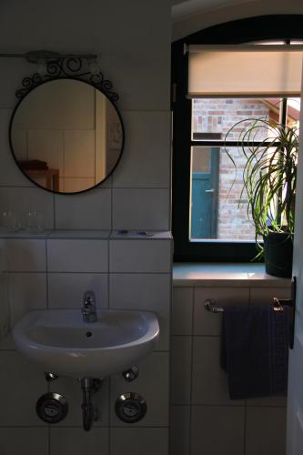 a bathroom with a sink and a mirror and a window at Pensionszimmer im Fliederhof in Michendorf