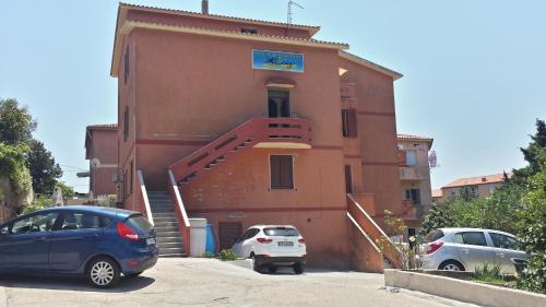 a building with two cars parked in front of it at Guest House Tra Rocce E Mare in La Maddalena