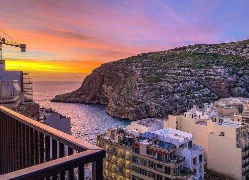 a sunset over a city with the ocean at Sun Sea Living Gozo in Xlendi