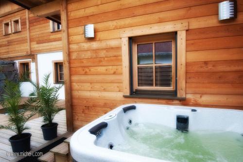 a bath tub in front of a wooden house at Les Adrets in Gérardmer
